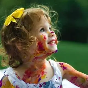 A happy kid covered in colorful paint.
