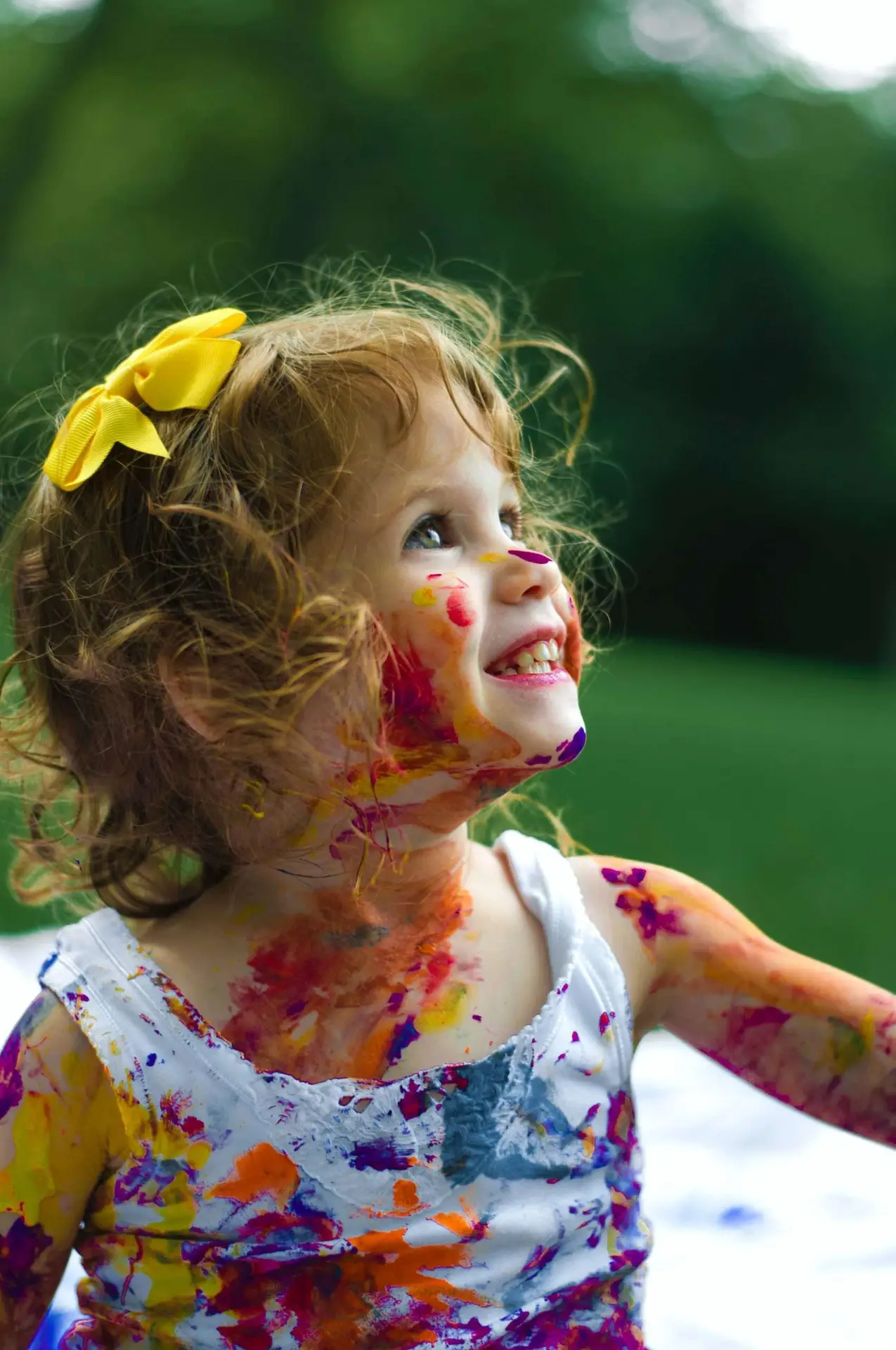 A happy kid covered in colorful paint.