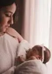 A photo of a mom holding her baby in his arm.