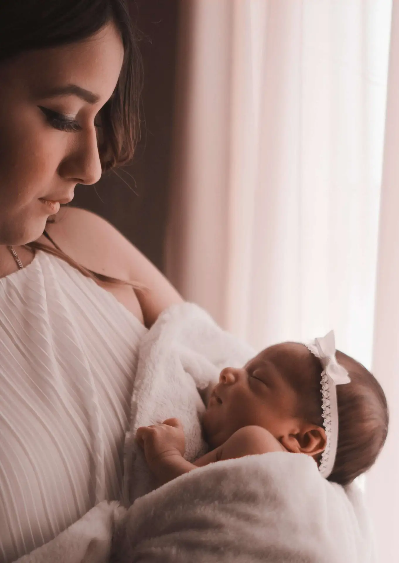 A photo of a mom holding her baby in his arm.