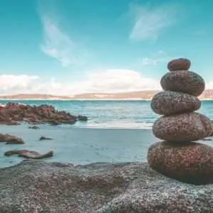 A scenic ocean view with a subject of a stacked stone in the shore.