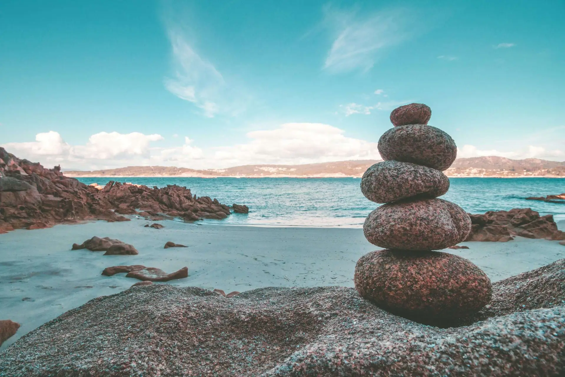 A scenic ocean view with a subject of a stacked stone in the shore.