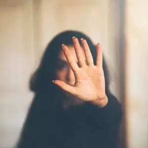 The image shows a woman with a hand stop sign