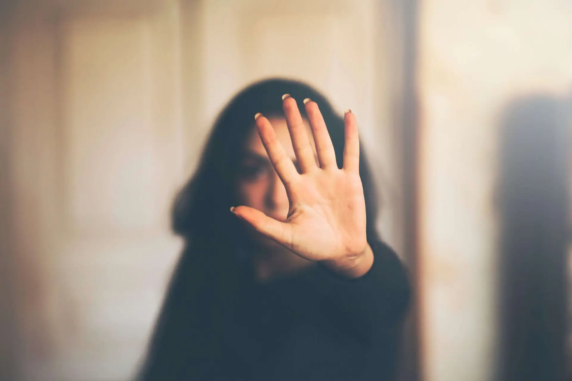 The image shows a woman with a hand stop sign