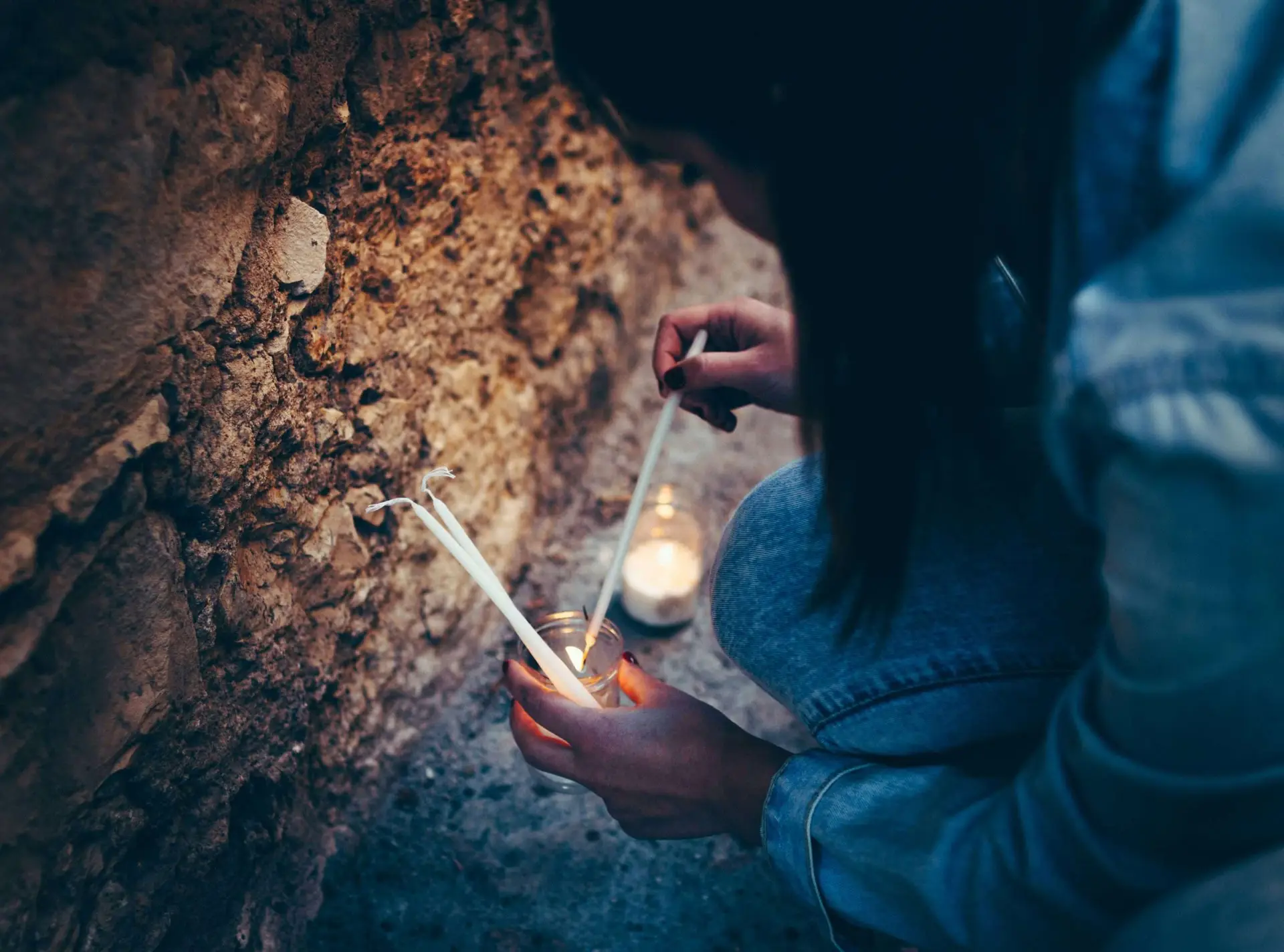 A woman lighting a candle while seated.