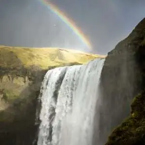 This image captures a breathtaking scene of nature's beauty, featuring a magnificent rainbow gracefully arching over a cascading waterfall.