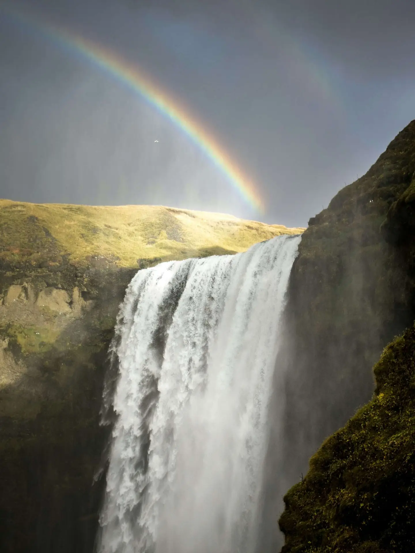 This image captures a breathtaking scene of nature's beauty, featuring a magnificent rainbow gracefully arching over a cascading waterfall.