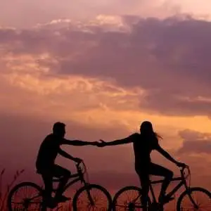 A creative photo of two lovers riding a bicycle on a field.