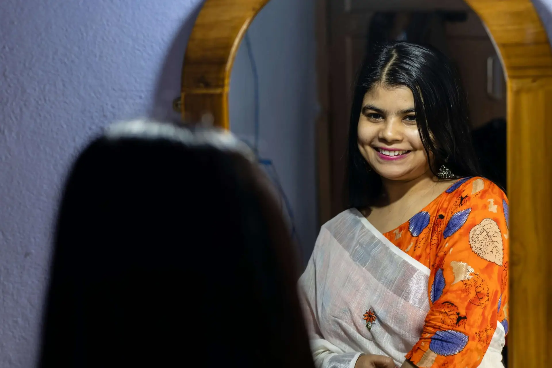A happy woman staring in a mirror.