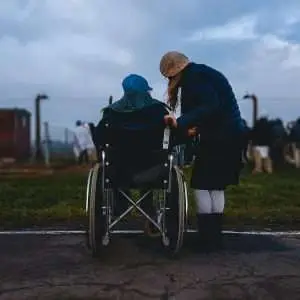 This is a lovely photo where the girl is accompanying her partner in wheelchair watching people around.