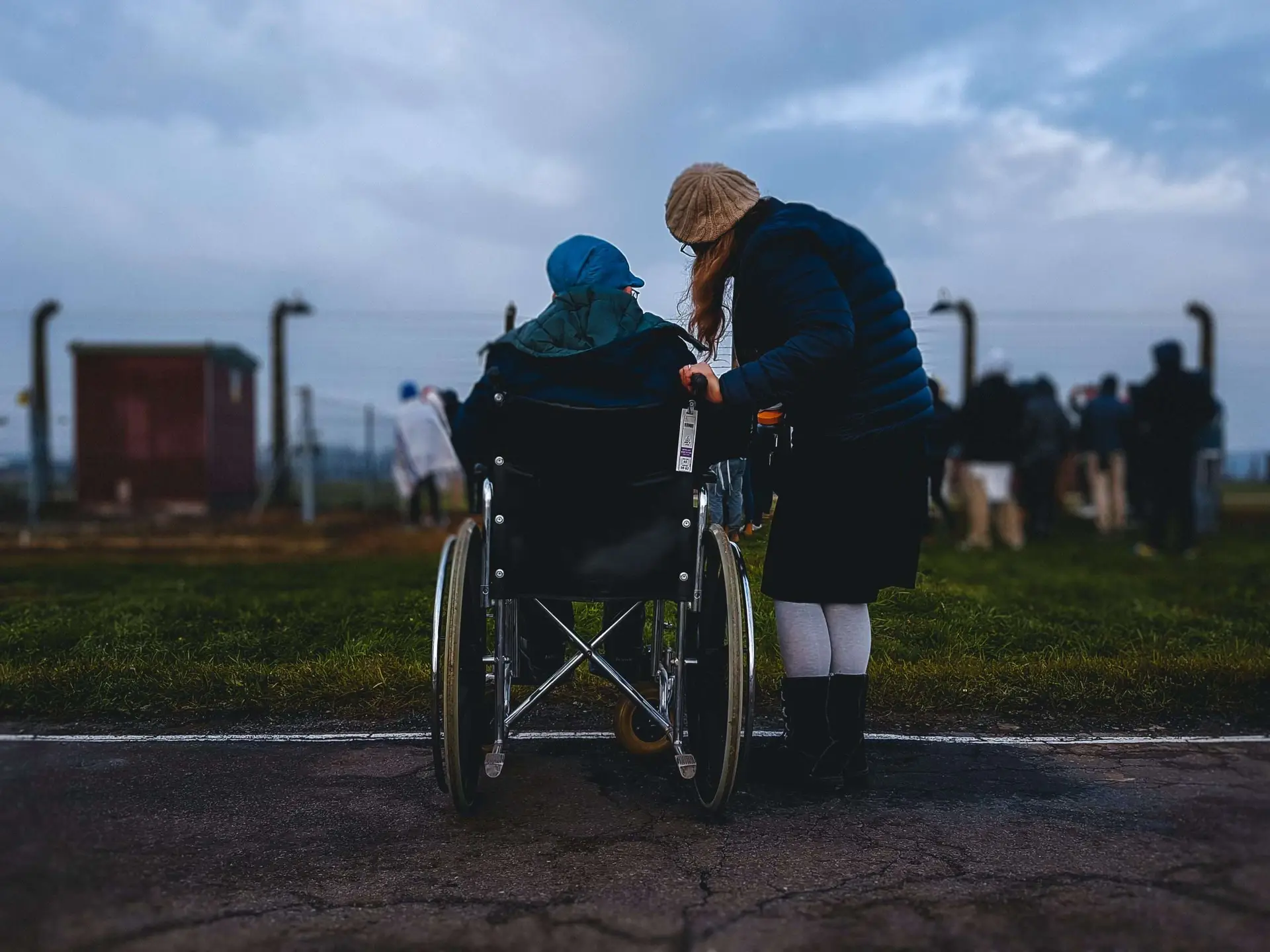 This is a lovely photo where the girl is accompanying her partner in wheelchair watching people around.